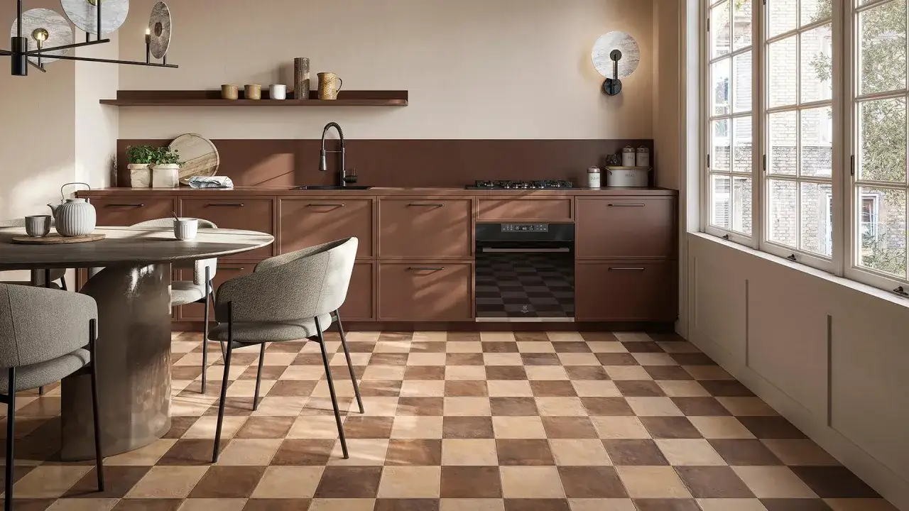 Cucina moderna con pavimento a scacchiera che crea una tabella colori caldi. Mobili marroni, tavolo rotondo e sedie grigie.