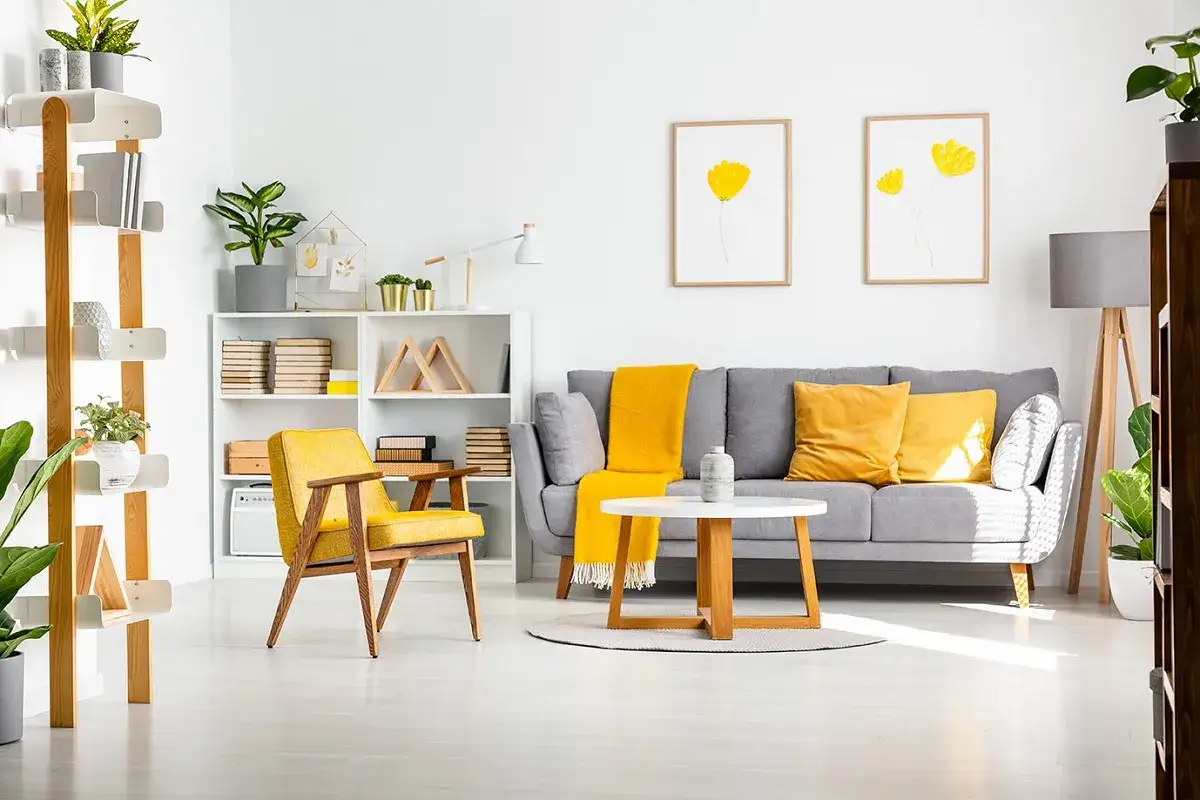 Un soggiorno moderno dove il grigio e giallo che colore esce, con divano, poltrona e cuscini in tonalità vivaci.