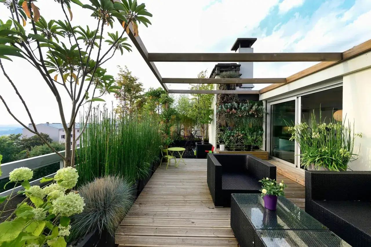 Un balcone trasformato in un lussureggiante terrazzo con mobili da esterno, piante rigogliose e un giardino verticale.
