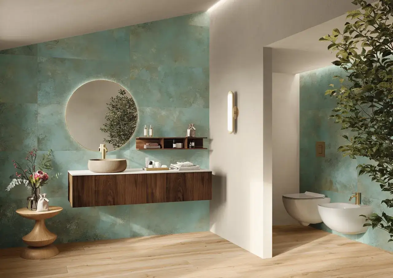 Elegante bagno verde e beige con lavabo in pietra, specchio rotondo illuminato e mobili in legno scuro.