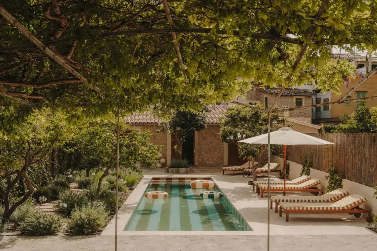 Un incantevole giardino di 50 mq con piscina, lettini prendisole e un pergolato ombroso.