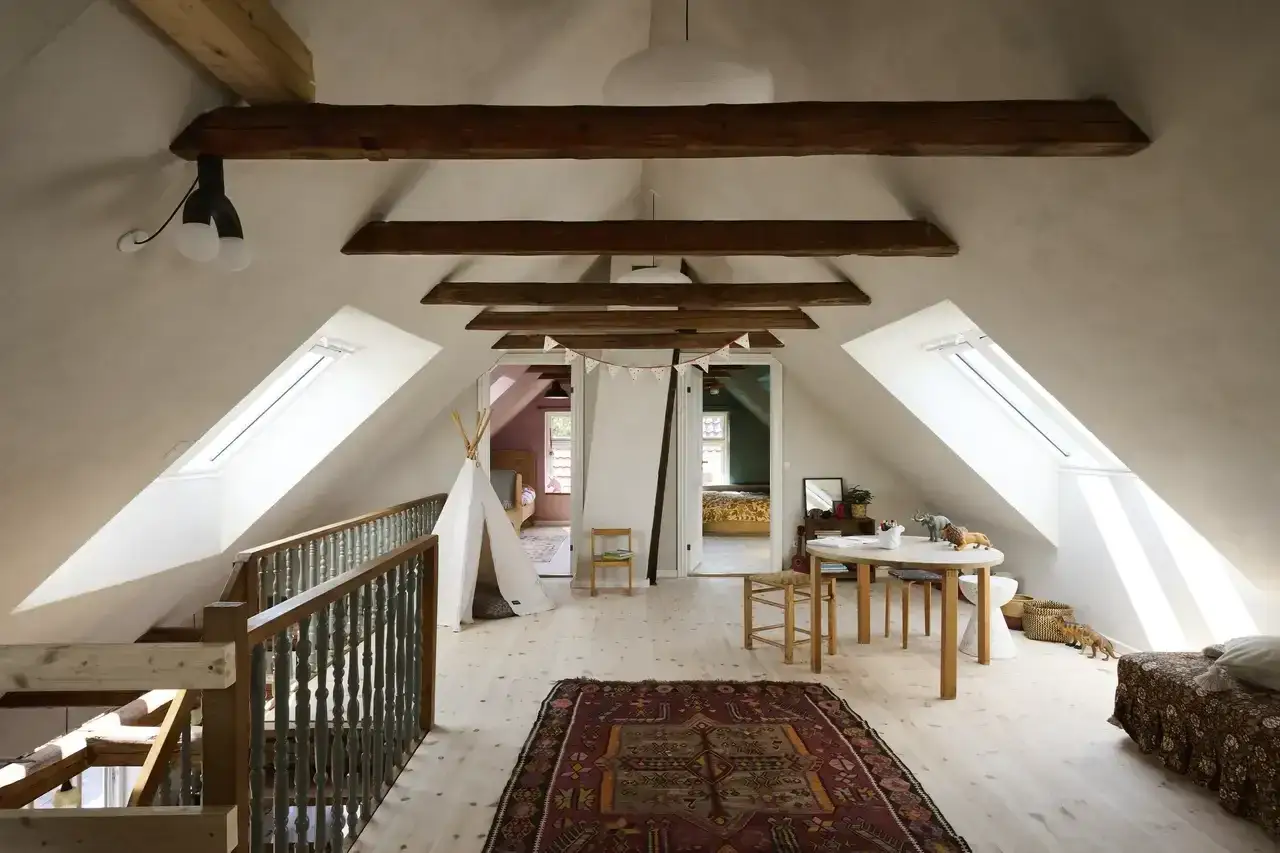 Idee per ristrutturare casa antica: mansarda luminosa con travi a vista, tappeto etnico, teepee e zona gioco.